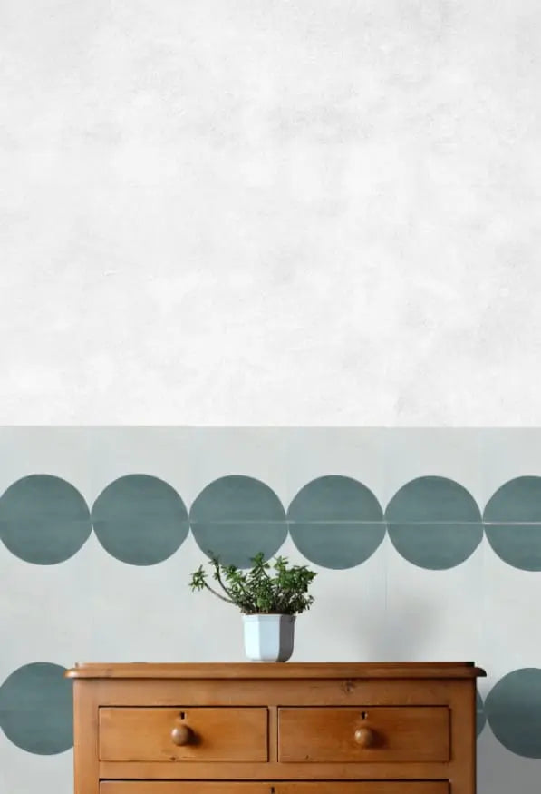 baldosa-hidraulica-mosaico-semicirculo-geometrico de color verde, pared blanca y una mesa de madera con una maceta encima.